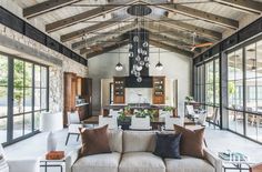 a living room filled with lots of furniture next to large windows and an open kitchen