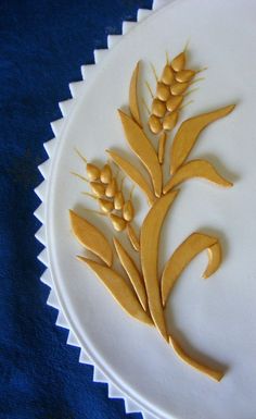 a cake decorated with wheat on top of a white plate and blue table cloth behind it