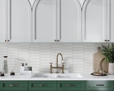 a kitchen with green cabinets and white tile backsplash, brass faucet