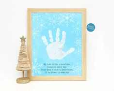 a christmas tree next to a framed print with a hand and footprints on the paper