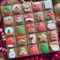 there are many decorated cookies in the box on the table next to some christmas decorations