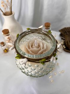 Clear bulbous jar with a green leaf and pearl garland tied around the rim. Jasmine scented soy candle in the shape of a rose on top. Candle With Crystals, Jasmine Candle, Jasmine Rose, Greenery Garland, Jar Candle, Glass Jar, Mason Jar, Glass Jars