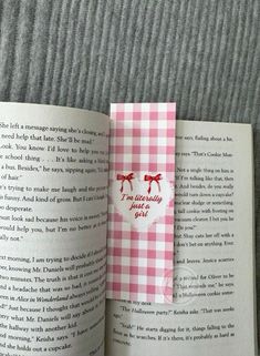 an open book with a pink and white checkered ribbon on it's cover