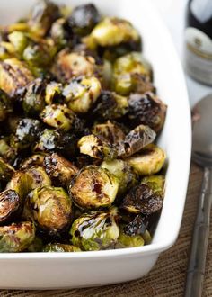 brussel sprouts in a white casserole dish with silverware