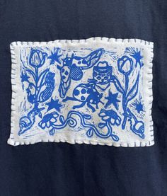 a blue and white embroidered square on a black shirt with an image of animals in the background