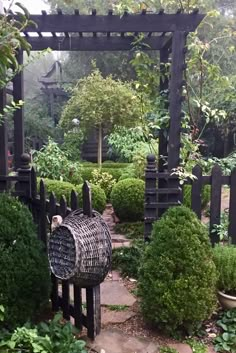 a bird cage sitting in the middle of a garden