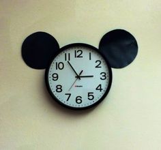 a mickey mouse clock on the wall with black ears and numbers in front of it