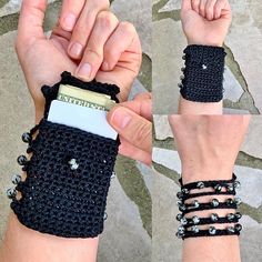 a hand holding a cell phone covered in lots of black beads and chain bracelets