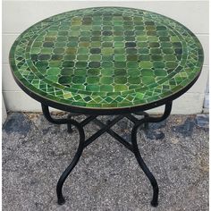 a green mosaic table sitting on top of a sidewalk