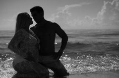 a man and woman are standing in the water at the beach with their backs to each other