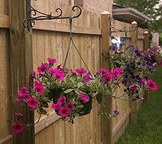 hanging flower pots on the side of a fence with purple and pink flowers in them