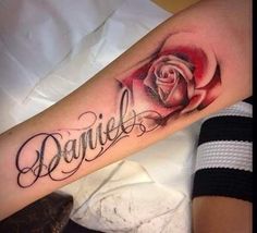 a woman's arm with a rose and the word danielle tattooed in cursive writing