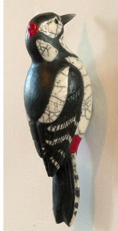 a black and white bird sitting on top of a wooden wall mounted hook with red eyes