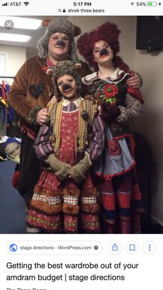 three people dressed up in costume posing for a photo together with clowns on the wall behind them