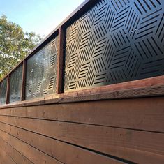 the side of a wooden building with metal grills on it's sides and trees in the background