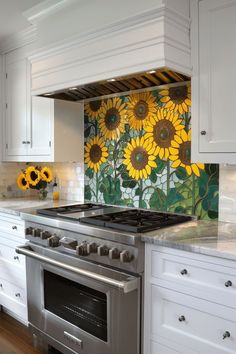 a kitchen with sunflowers painted on the backsplash and stainless steel stove