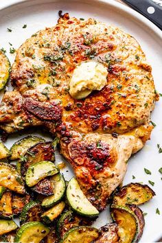 a white plate topped with chicken, zucchini and potatoes