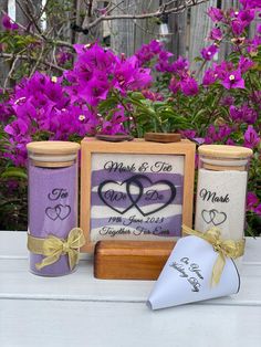 two jars with hearts on them sitting next to purple flowers