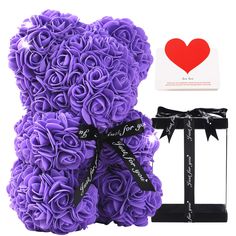 a purple teddy bear sitting next to a gift box