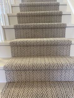 a carpeted staircase with white handrails and black and white herringbone pattern