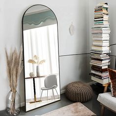 a mirror sitting on top of a wall next to a chair and ottoman in a living room