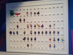 legos are arranged in rows on a white display case against a blue and purple wall