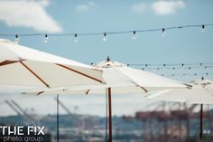 several white umbrellas with string lights above them on the roof of an outdoor restaurant