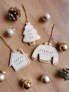 personalized christmas ornaments on a wooden table with baubles and pineconis