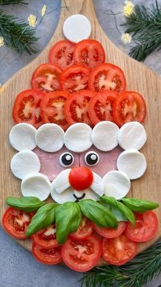 a wooden cutting board topped with sliced tomatoes and cheese covered in the face of santa claus