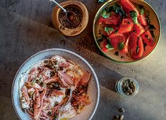 a plate with meat and vegetables on it next to two bowls filled with sauces