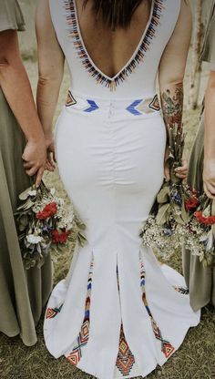 the back of a woman's dress with flowers in her hand and three other women holding bouquets