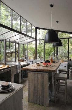 an open kitchen and dining area with lots of glass doors on the walls, windows in the ceiling