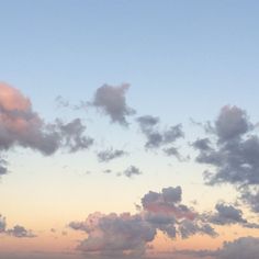 an airplane is flying in the sky at sunset or dawn with clouds and blue water