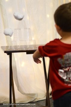 a young boy standing in front of a table with white balls on top of it