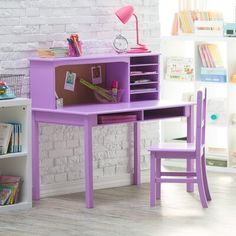 a child's desk and chair in front of a white brick wall with bookshelves