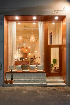 a store front with two couches in the window and some lights on above them