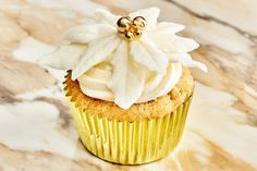 a cupcake with white frosting and a flower on top is sitting on a marble surface