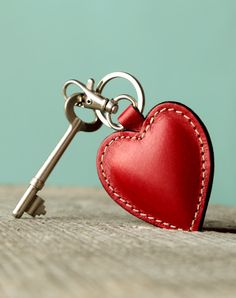 a red heart shaped keychain with a silver skeleton on it's side