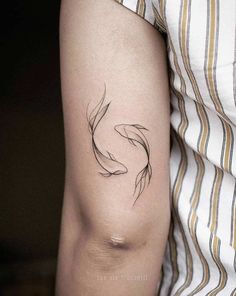 a woman's arm with a black and white fish tattoo on the left side