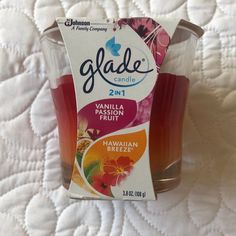 a package of fruit juice sitting on top of a white bed sheet with the label glade candle 2 in 1 vanilla passion fruit