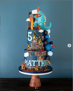 a three tiered cake decorated with legos and other toys on a wooden table