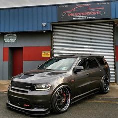 a grey car parked in front of a building with red and black stripes on it