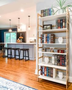 a living room filled with furniture next to a kitchen and dining room table covered in books