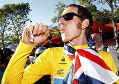 a man drinking from a wine glass while wearing a yellow shirt and sunglasses with an american flag on it