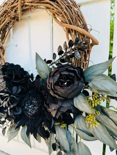 a wreath with black flowers and greenery