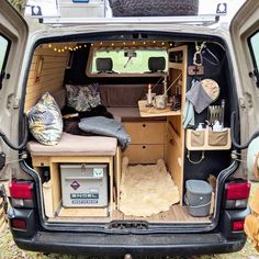 an open camper van with the back door opened and camping supplies in the cargo area