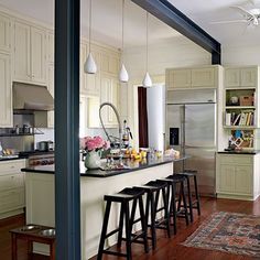 a kitchen with an island and bar stools next to the counter top in front of it