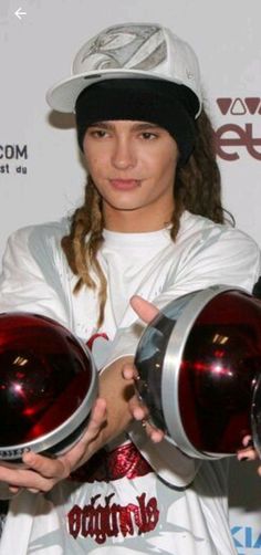 a woman is holding two red helmets in her hands