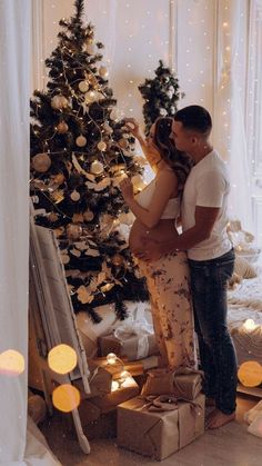 a man and woman standing in front of a christmas tree