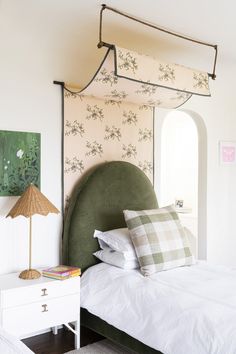 a bed with white sheets and green headboard